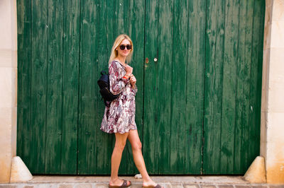 Portrait of woman standing against wooden fence