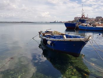 Fishing boat moored at harbor against sky