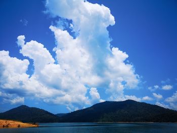 Scenic view of sea and mountains against blue sky