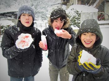 Portrait of happy boys wearing warm clothing eating food during winter