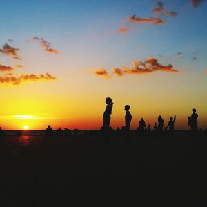 Silhouette people at beach against sky during sunset