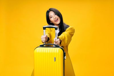 Portrait of smiling young woman against yellow background