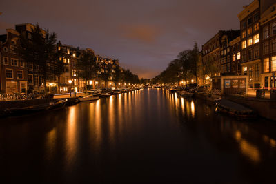 River by illuminated city against sky at night