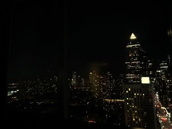 Illuminated buildings in city against sky at night
