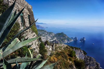 Scenic view of sea by mountains against blue sky