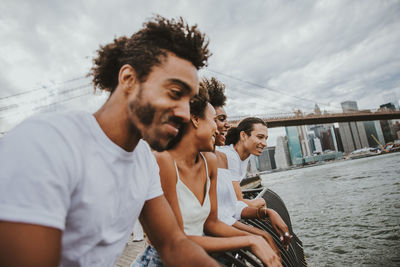 Young man smiling while sitting in boat against sky