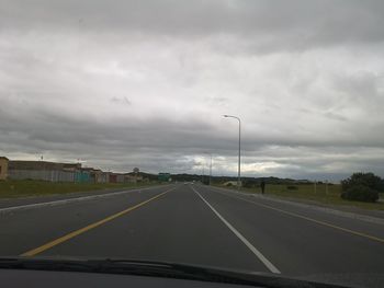 Road against cloudy sky seen through car windshield