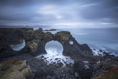 Rock formation in sea against sky