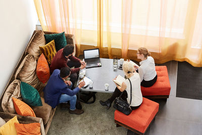 High angle view of male and female entrepreneurs discussing while sitting by table at workplace