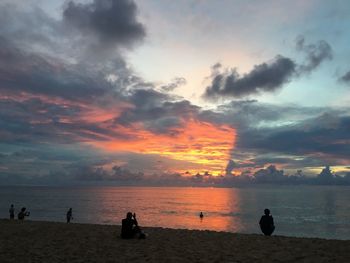 Silhouette people on beach against sky during sunset