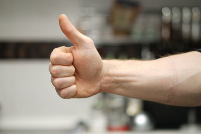 Cropped hand of person gesturing thumbs up sign outdoors