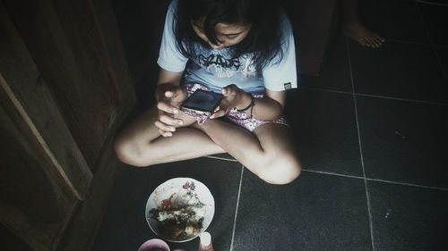 Low section of woman sitting on floor at home