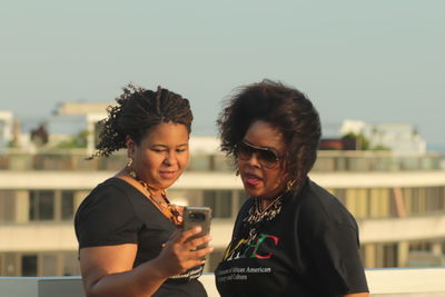 Young woman using mobile phone against sky