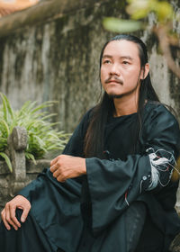 Portrait of young man looking away while standing outdoors