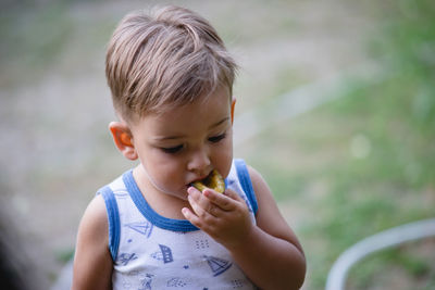 Baby boy eating food while standing outdoors