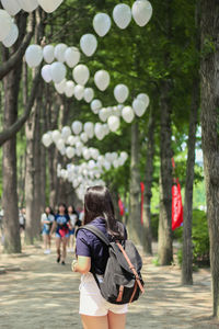 Rear view of woman with backpack standing on footpath