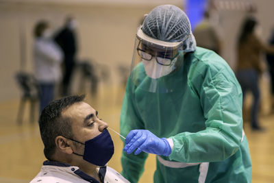 Doctor wearing protective suit examining man