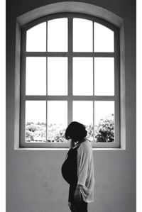 Side view of pregnant woman walking by window