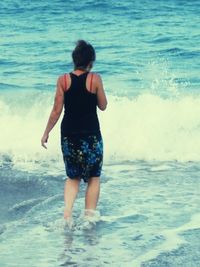 Rear view of boy on beach against sky