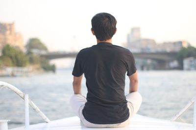 Rear view of man sitting on boat against sky