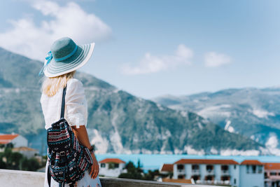 Rear view of woman standing by sea against mountains