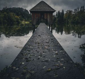 Walkway by lake against sky