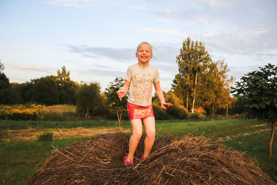Portrait of a little girl  standing on haystack.