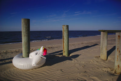 Wooden posts on beach against sky