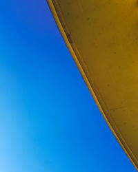 Low angle view of crane against clear blue sky