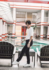 Full length side view of smiling young woman standing against building