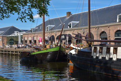 Sailboats moored on canal by buildings in city against sky