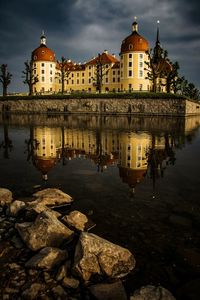 Reflection of building in lake against sky in city