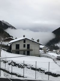Houses by snow covered mountain against sky