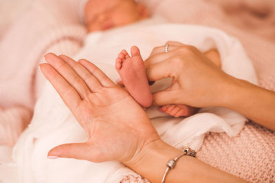 Mother measuring hand by baby leg at home