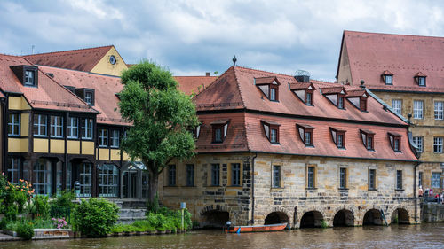 Canal in city against cloudy sky