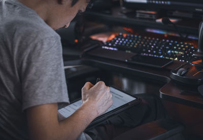 A caucasian guy sits in a work chair and chooses a menu by moving a black pen on a tablet