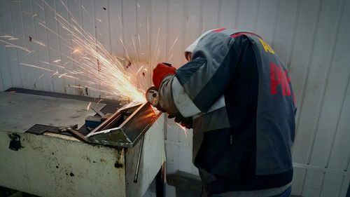 Side view of worker welding metal in workshop