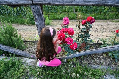 Girl smelling flowering plant on field