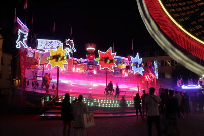 Group of people in amusement park at night