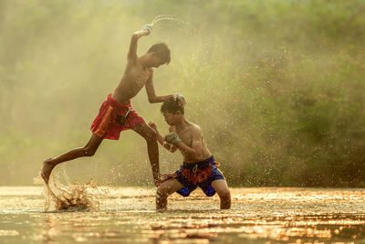 Shirtless boys playing in swamp