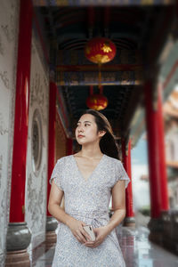 Young woman looking away while standing in corridor