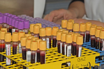 Midsection of person by bottles on table