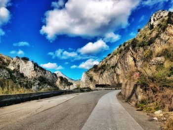 Road passing through mountains against cloudy sky