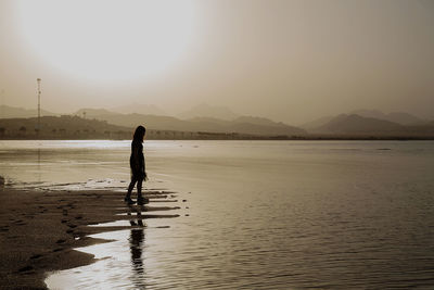 Girl standing on beach against sky