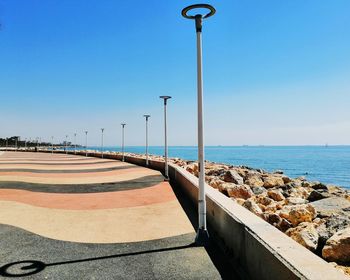 Street by sea against clear blue sky