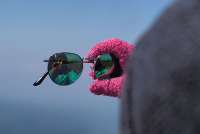 Cropped hand of woman holding sunglasses with reflection