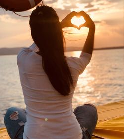 Rear view of woman at beach during sunset