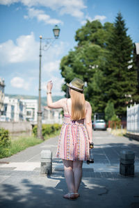 Rear view of woman on road against sky in city