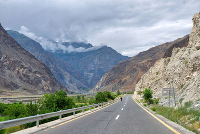 Empty road by mountains against sky