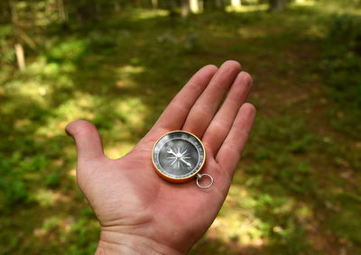 Close-up of hand holding clock against blurred background